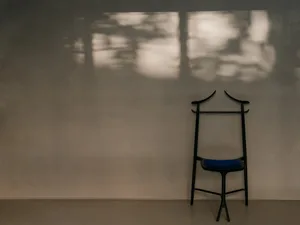 Modern black wooden chair with a blue cushion in an interior space with natural light.