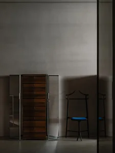 Modern interior design featuring a wooden wardrobe and a black valet stand with blue cushion.