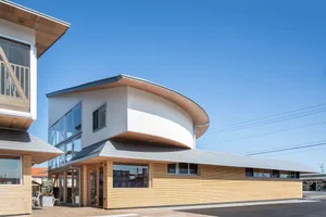 Modern storefront building with a metal-clad facade featuring large glass windows and a curved roof design.