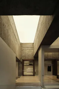 Modern minimalist interior design featuring concrete walls and open ceiling space.