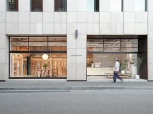 Modern retail storefront with concrete and glass materials, featuring clothing display.