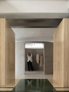 A minimalist closet with concrete walls and a hanging rail for clothes.