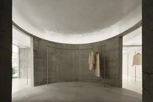 Interior of a minimalist clothing boutique with concrete walls and floor.