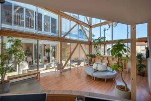 Modern interior design featuring a living room with wood flooring and large glass walls.