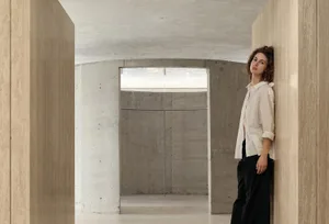 A minimalist interior scene featuring concrete walls and a light source through a window.