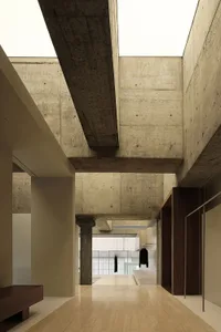 A spacious, minimalist interior with exposed concrete walls and large, open spaces.