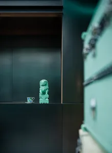 A ceramic lion statue and a small decorative vase displayed on a dark shelf.