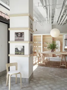 A minimalist retail space featuring wooden elements and shelves with books, clothing, and other items.