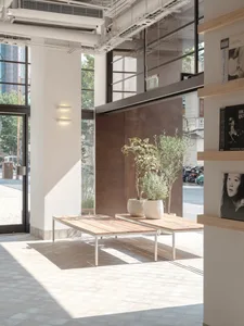 A modern lobby with closed glass windows, wooden tables, and concrete flooring.