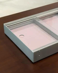 Metal product storage unit with glass top on wooden table