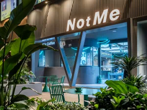 Modern glass storefront of a coffee shop with sleek metal accents and concrete flooring.