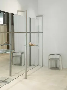 Modern retail display area featuring glass and metal shelving and seating arrangements.