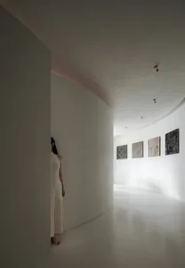A minimalist interior with white cast concrete walls, curved walls, and artwork on the walls.