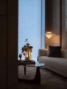 A cozy and contemporary living room featuring modern furniture, a floor lamp, and a glass table.