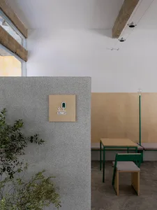 A minimalist restaurant interior featuring a textured concrete counter with green accents.