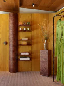 A beautifully styled retail display featuring wooden shelves and a green dress hanging on a wooden rack.