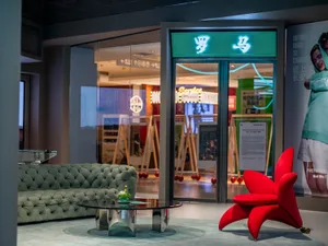 Modern retail store interior with glass walls, metal accents, and a green couch.
