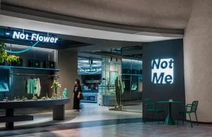 Modern retail storefront featuring greenery, concrete, and glass materials.