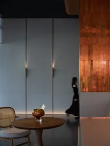 A minimalist restaurant interior featuring metallic tiles, wood, and glass.