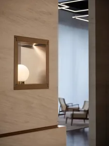 A minimalist lighting frame with a frosted glass sphere on a textured wall.