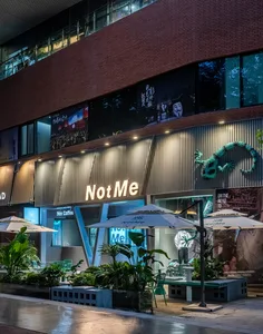 The exterior of a modern retail storefront featuring aluminum siding, large windows, and greenery.