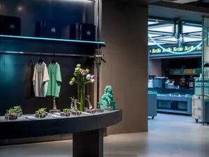 A retail storefront with a concrete theme and a vase with purple flowers on a table.