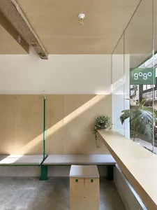 A modern cafe interior with wooden seating and concrete flooring.
