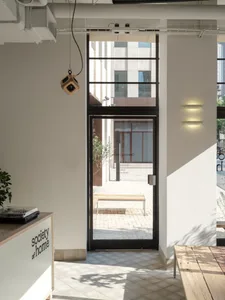 A modern industrial cafe entryway featuring glass doors and minimalist design