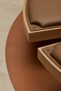 Close-up of a modern interior design featuring a wooden furniture piece with leather accents and metal rivets.