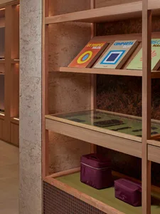 Modern library with wooden bookshelves, glass display cases, and colorful books.