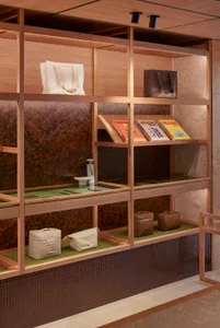Modern retail storefront with wooden laminate shelving displaying bags and books.
