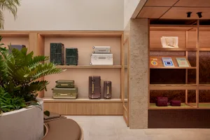 Retail storefront featuring wooden shelves, stone planters, and metal luggage cases.