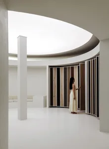 A modern lounge area featuring a curved white ceiling and a wall adorned with various wood panels.