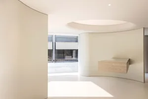 A minimalist white interior with curved walls and a light fixture.