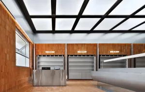 Modern industrial storefront featuring metallic counter, wooden shelves, and concrete floor.