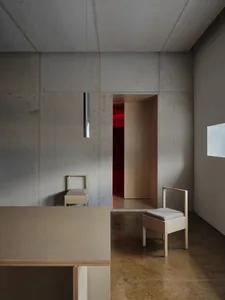 Minimalist interior design featuring modern concrete walls and simple wooden furniture.