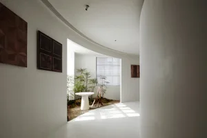 現代住宅室內空間，搭配極簡裝飾，特色為白牆、圓桌與小型花園。