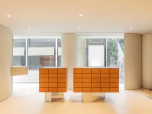 A modern retail storefront with orange backlit storage units and white columns.