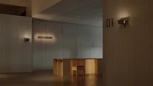 A minimalist lobby with concrete textures, featuring a desk and seating area.