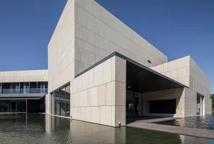 A modern building made of concrete with a minimalistic design, featuring clean lines and large windows.