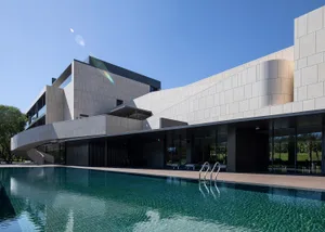 Modern architectural building with a stone exterior featuring clean lines and a curved design.