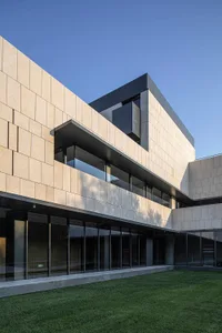 Modern architectural design featuring concrete exteriors with large glass windows, set against a clear blue sky.