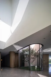 A modern lobby featuring glass walls and concrete pillars.