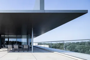 A modern terrace with a concrete roofline overlooking greenery.