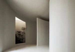 Modern minimalist interior design featuring white curved walls and floor-to-ceiling windows.