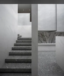A minimalist interior with concrete staircase and wall surfaces.