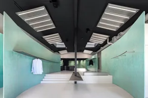Modern retail store with a grey concrete wall displaying clothing