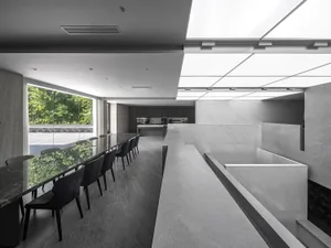 Modern conference room with long table and chairs, marble floor and walls, and ceiling lights.