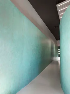 Modern interior corridor with concrete walls and illuminated lighting fixtures.