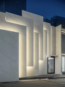 Modern storefront with illuminated marble columns at night.